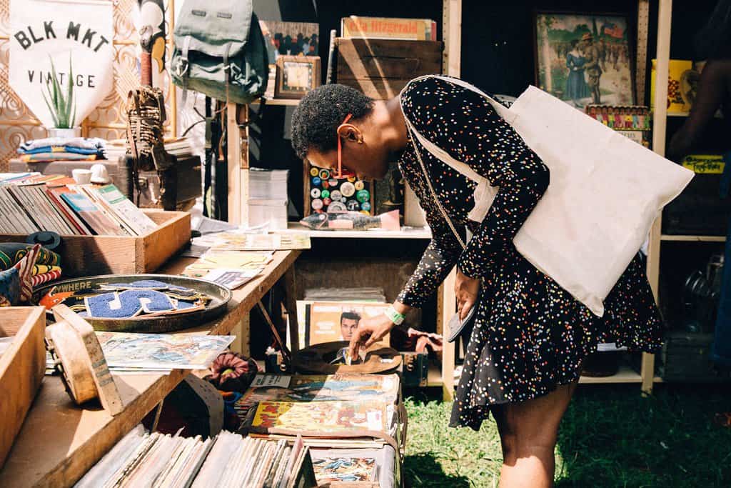 A woman in a black dress bends over to look at a retail display in BLK MKT Vintage's shop.