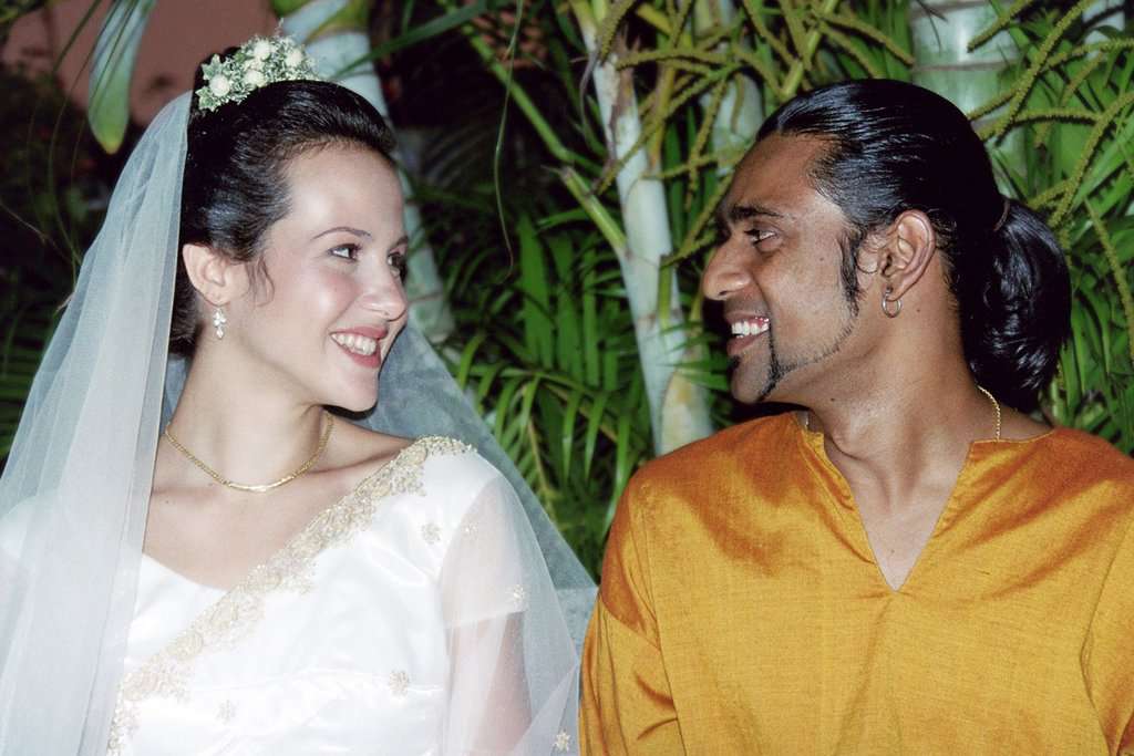 Wedding portrait of Chas Organics founders Marise May and Chanaka Kurera. Marise is wearing a traditional western wedding gown and Chanaka is wearing an orange saree.