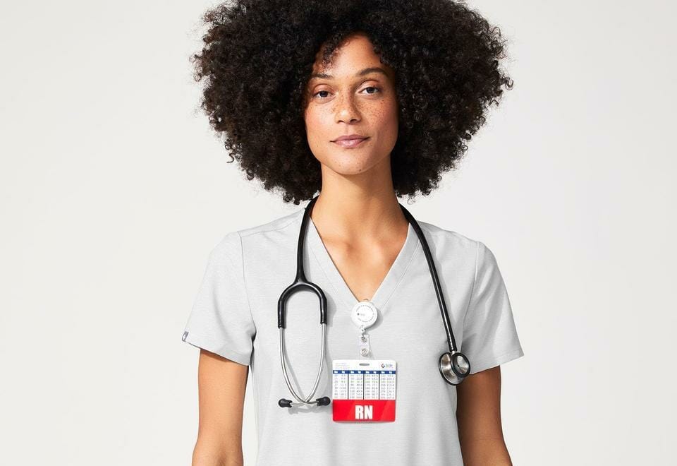 Portrait of a woman wearing FIGS medical scrubs and a nurse badge