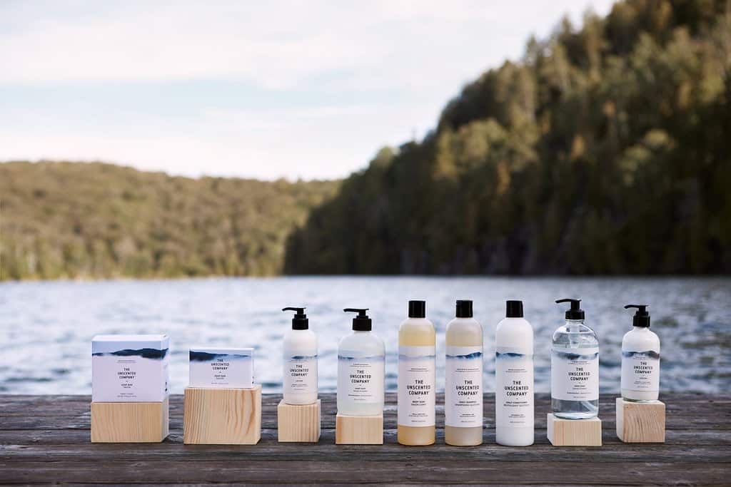 The Unscented Company products lined up on a wood plank backed by the mountains.