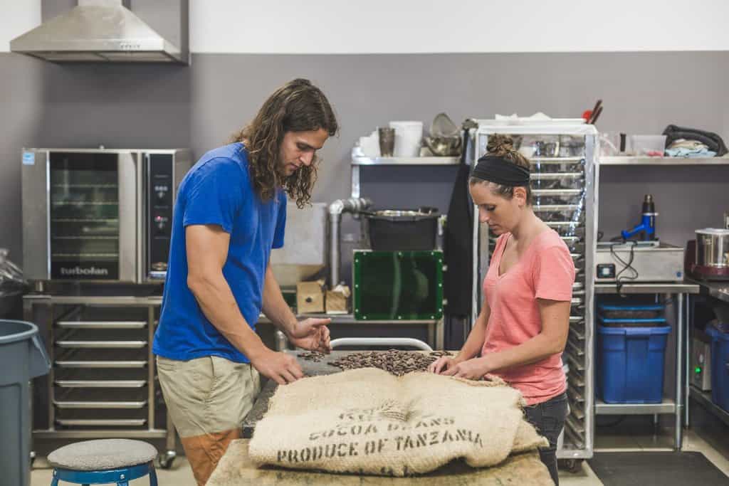 Two people work in a commercial kitchen producing chocolate bars