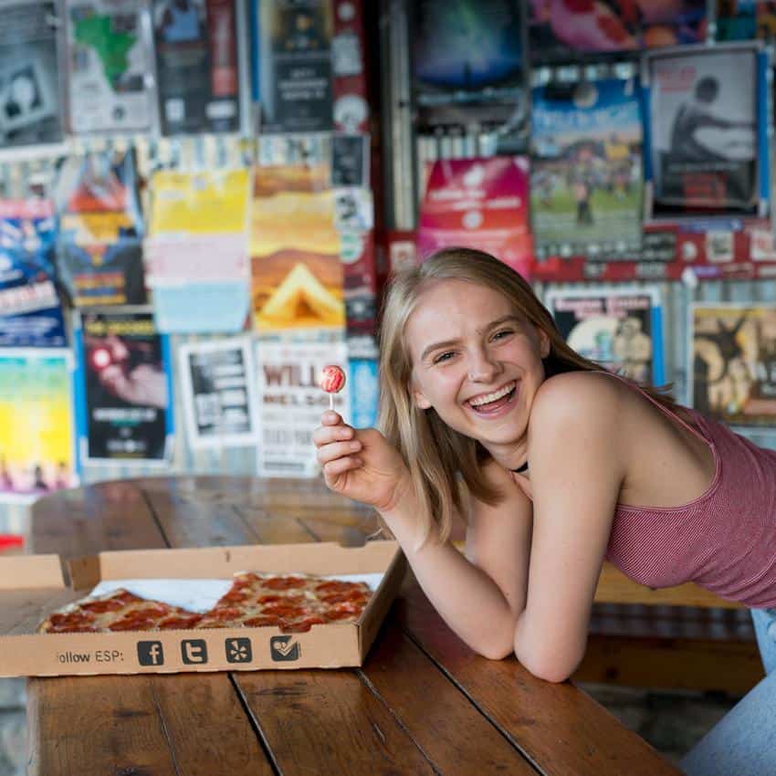 Woman smiles holing a lollipop in a pizza parlour