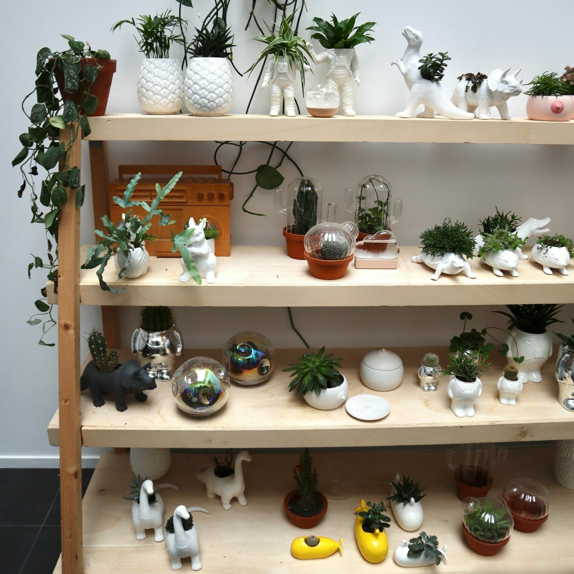 A collection of planters created by Bitten Design in the shapes of dinosaurs, astronauts, and squirrels.