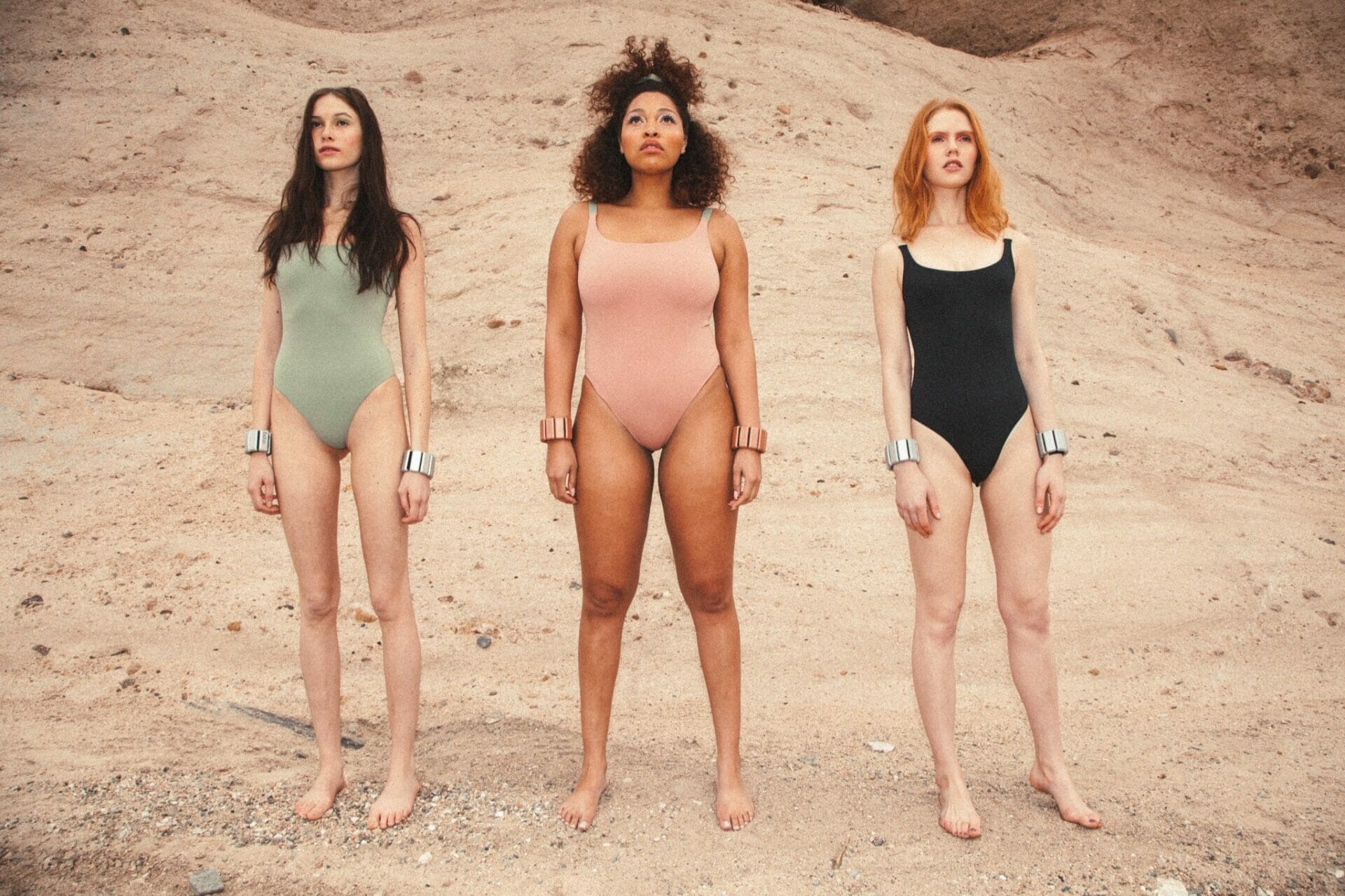 Three models wearing workout bodysuits and Bala Bangles in the desert.