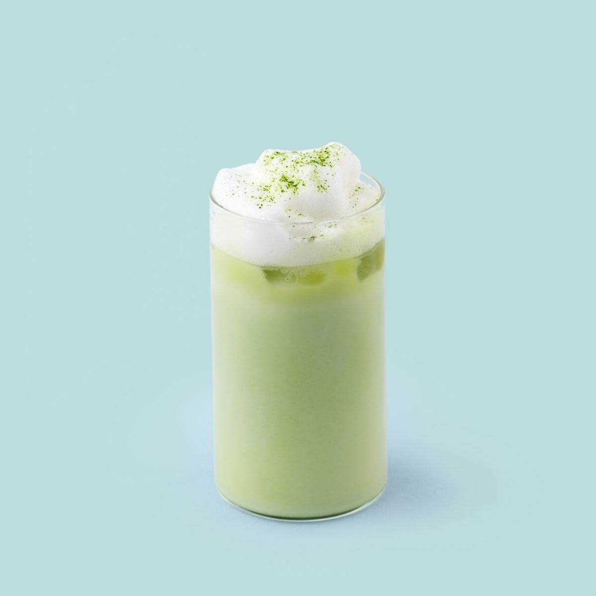 A glass of matcha latte with foam made with PureChimp’s matcha powder.