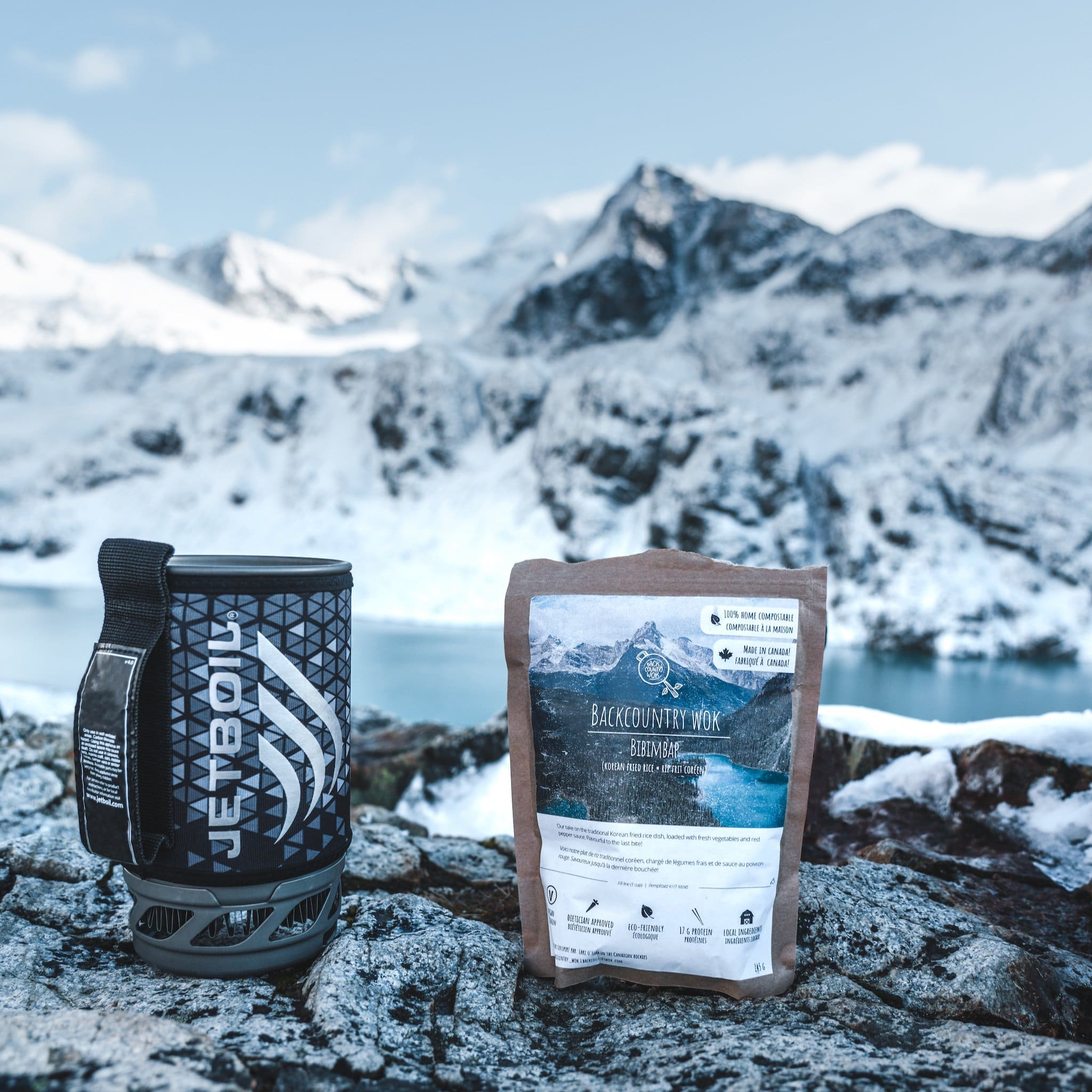 A package of Backcountry Wok's meals backdropped by snowcapped mountains.