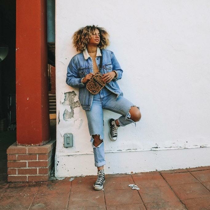 A model displaying a leopard print bag by Thread Wallets against a white wall.