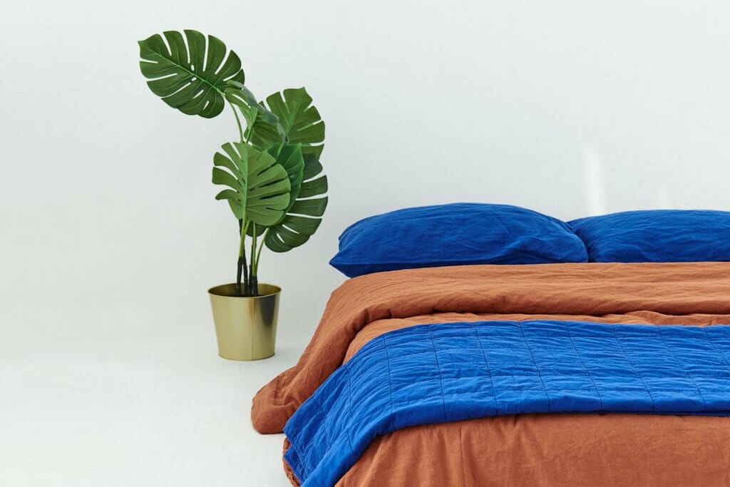 A bed with bright blue and copper bedding