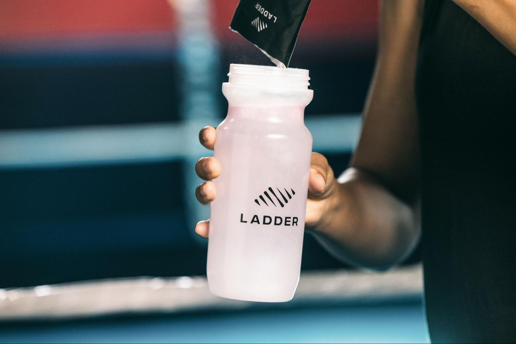A model with a Ladder water bottle pouring in Ladder’s nutrition powder into it.