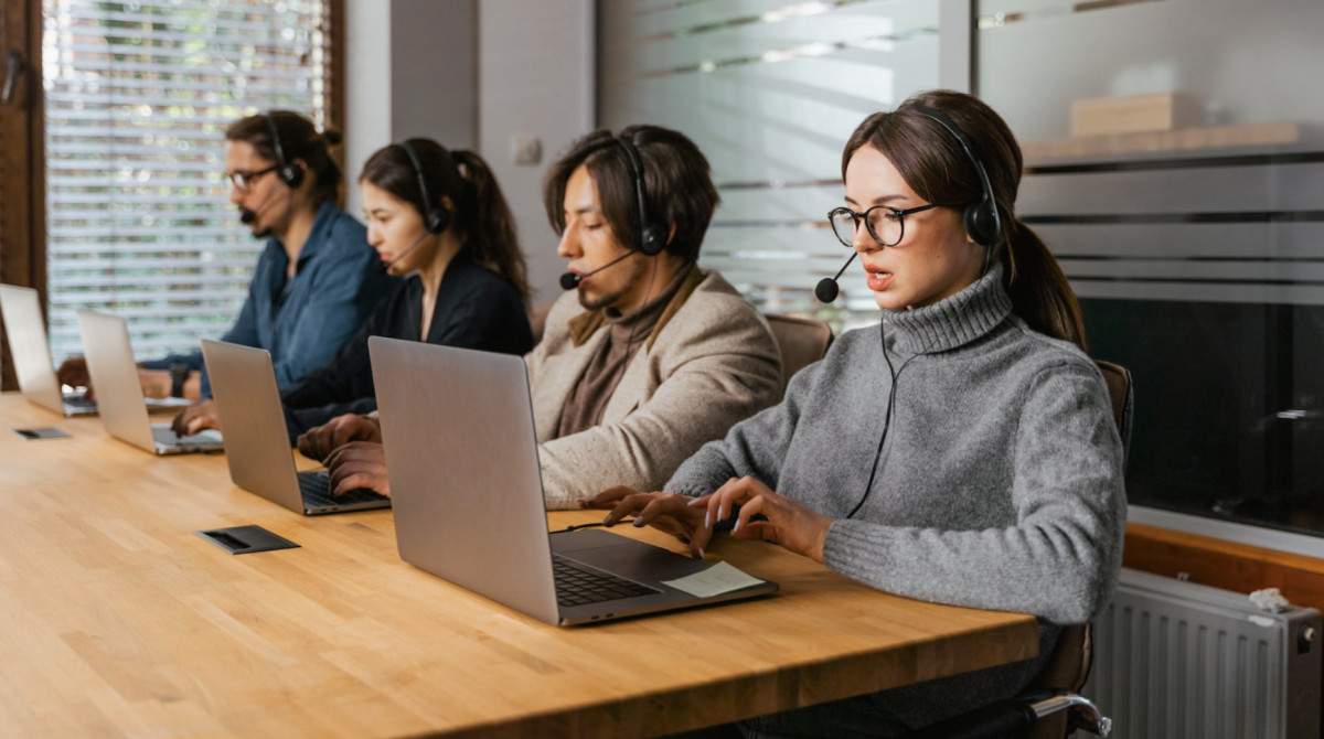 A group of women working on laptops in a conference room, focused on DTC marketing for Shopify.