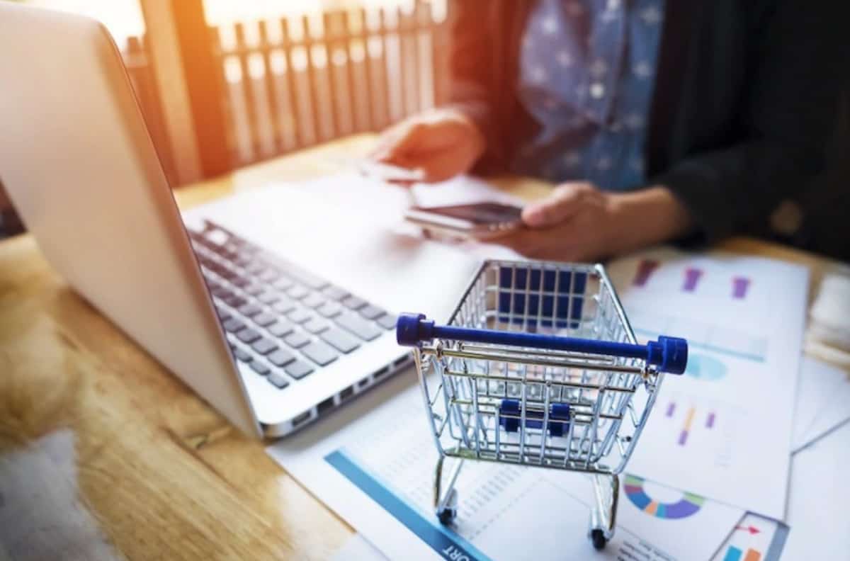 A woman is sitting at a desk with a shopping cart in front of her, implementing dropshipping strategies to improve sales in ecommerce.
