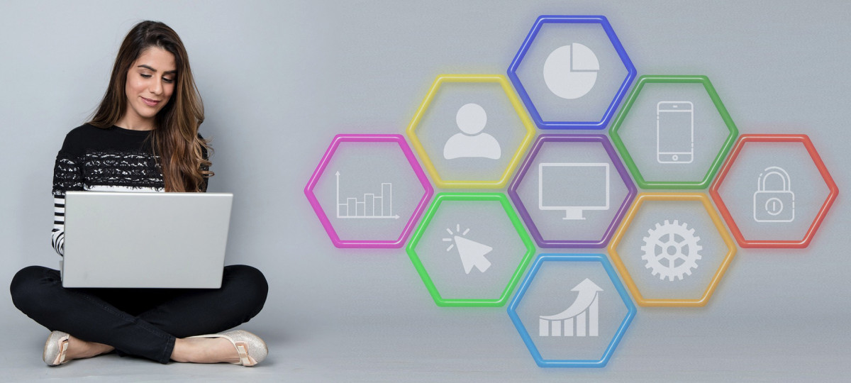 A woman is sitting on the floor with a laptop in front of colorful hexagons, exploring top ecommerce platforms and channels.