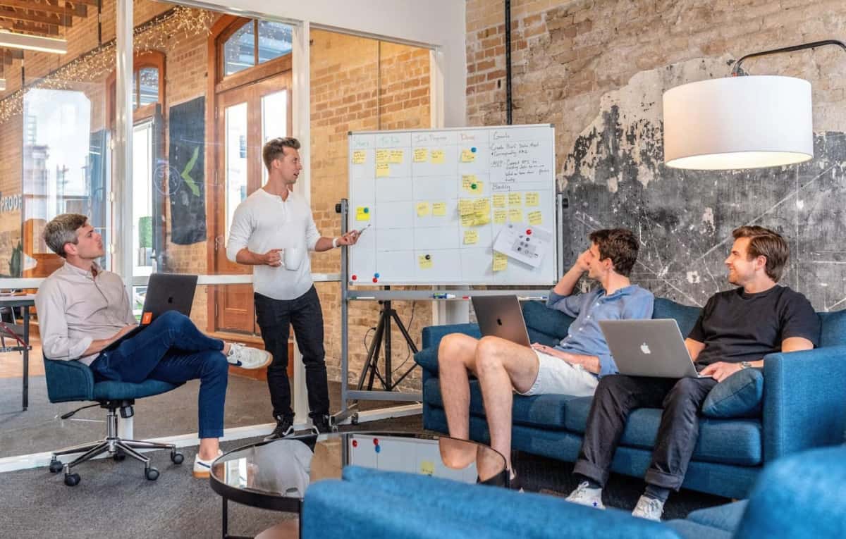 A group of people sitting around a table in an office discussing ecommerce strategies for their DTC marketing.