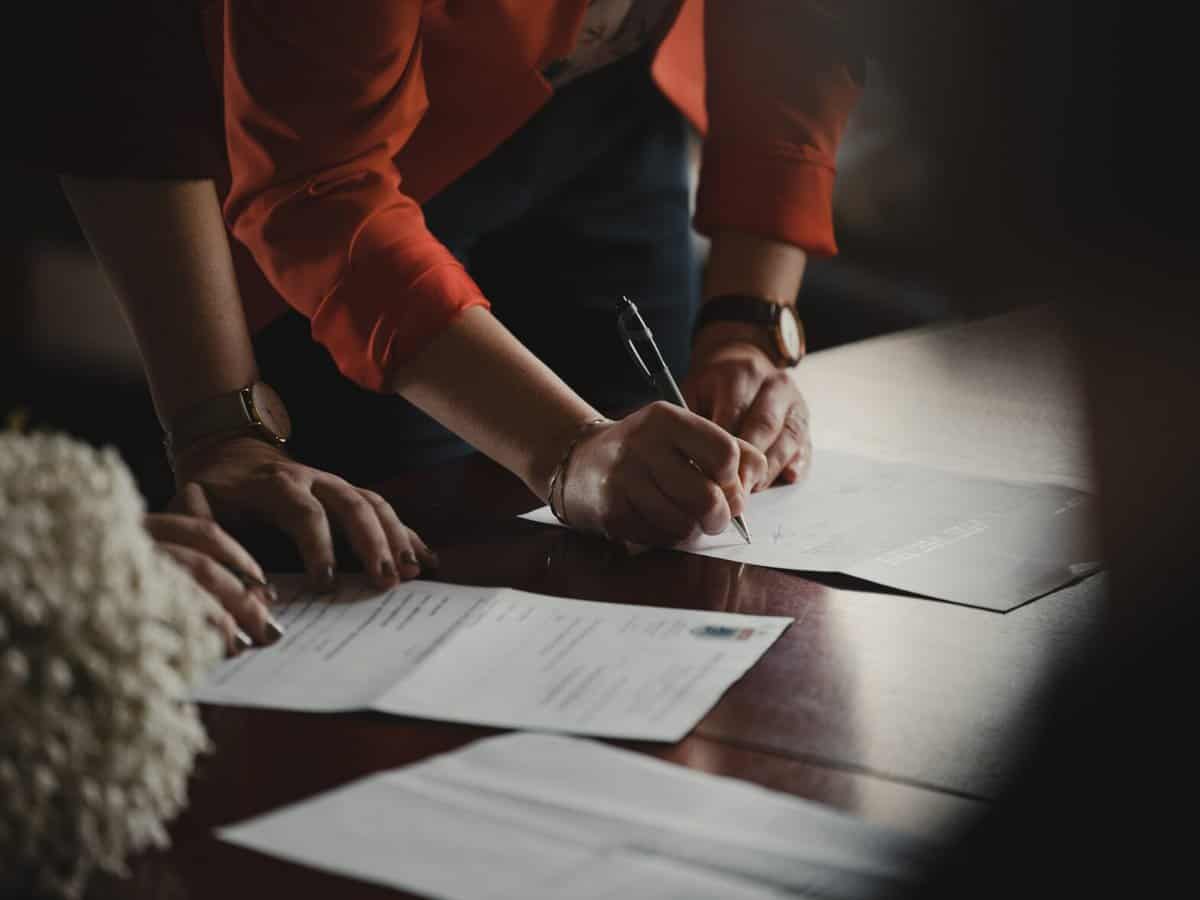 Two small business owners signing a document at a table.