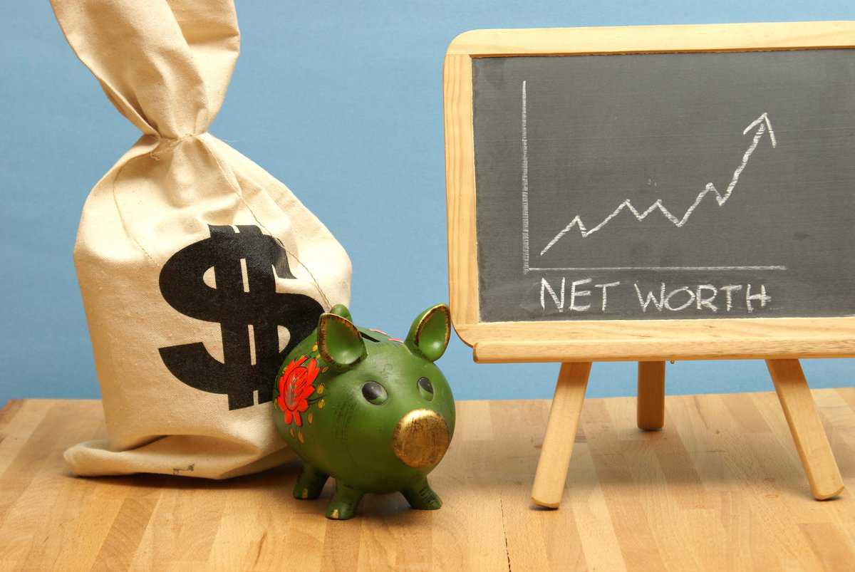 A piggy bank next to a bag with a dollar sign, symbolizing an increase in net worth.