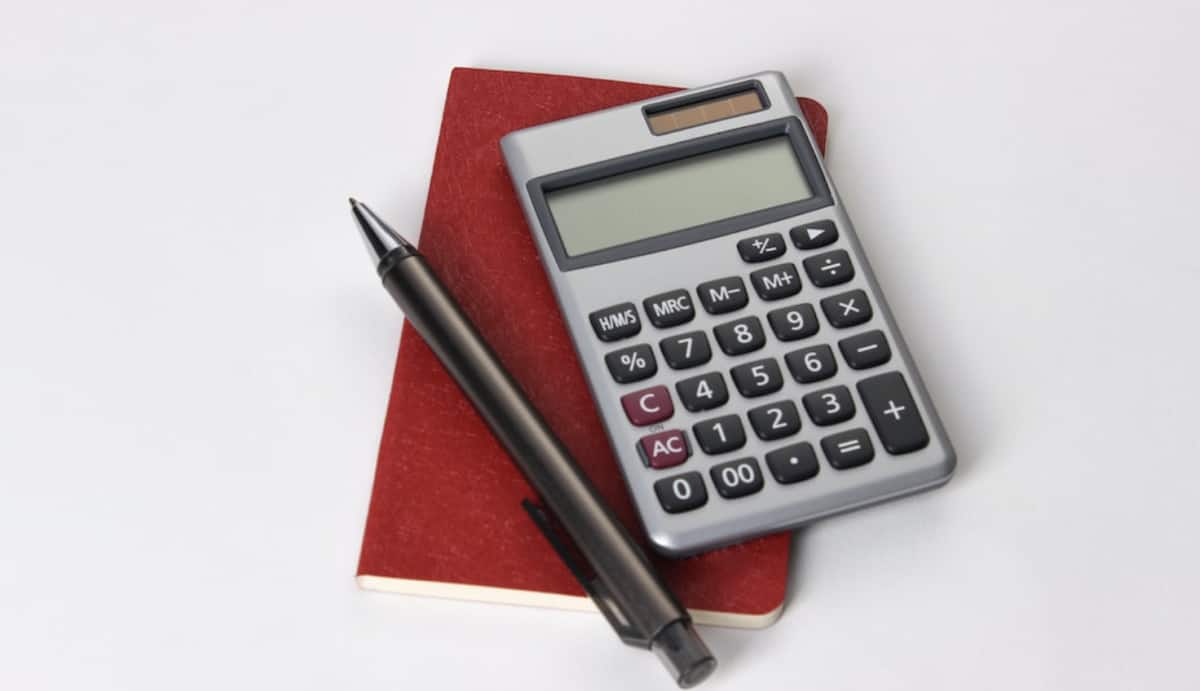 A calculator and pen sit on a notebook, ready for business use.