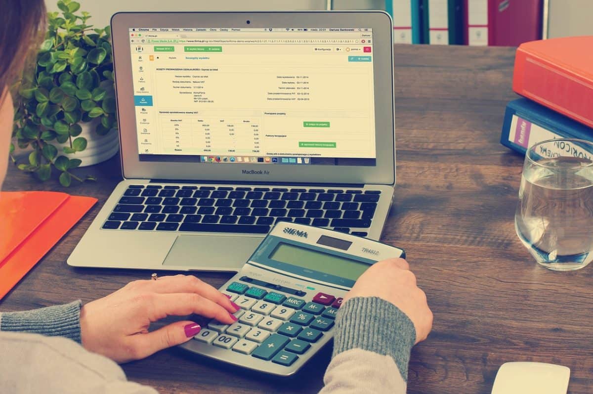 A woman at a desk with a laptop, calculating for financial advising.
