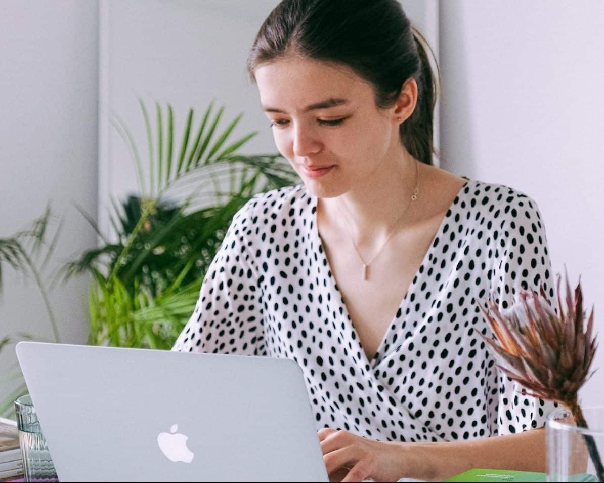 A woman using ChatGPT to work on her laptop at home.