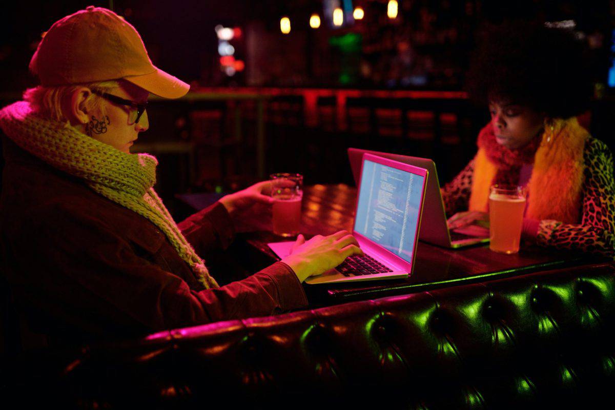 A man and a woman overcome challenges while using laptops in a bar.