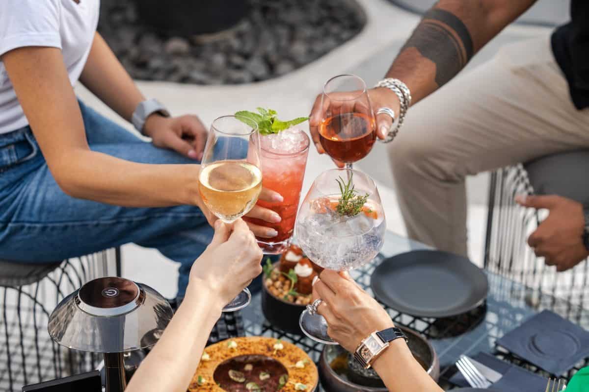 A group of people toasting drinks at a summer outdoor table.