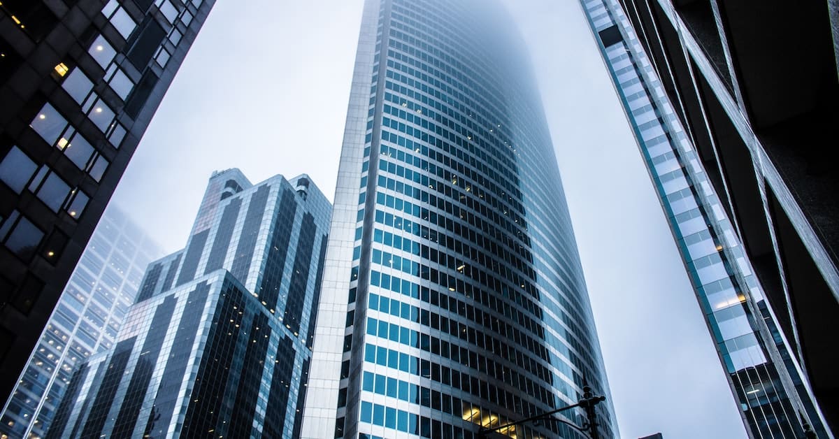 Skyscrapers with reflective glass facades reaching into a foggy sky, creating a scene of modern urban architecture akin to choosing the right trading platform.