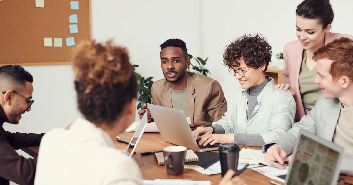A group of people sitting around a table, utilizing technology to optimize space.