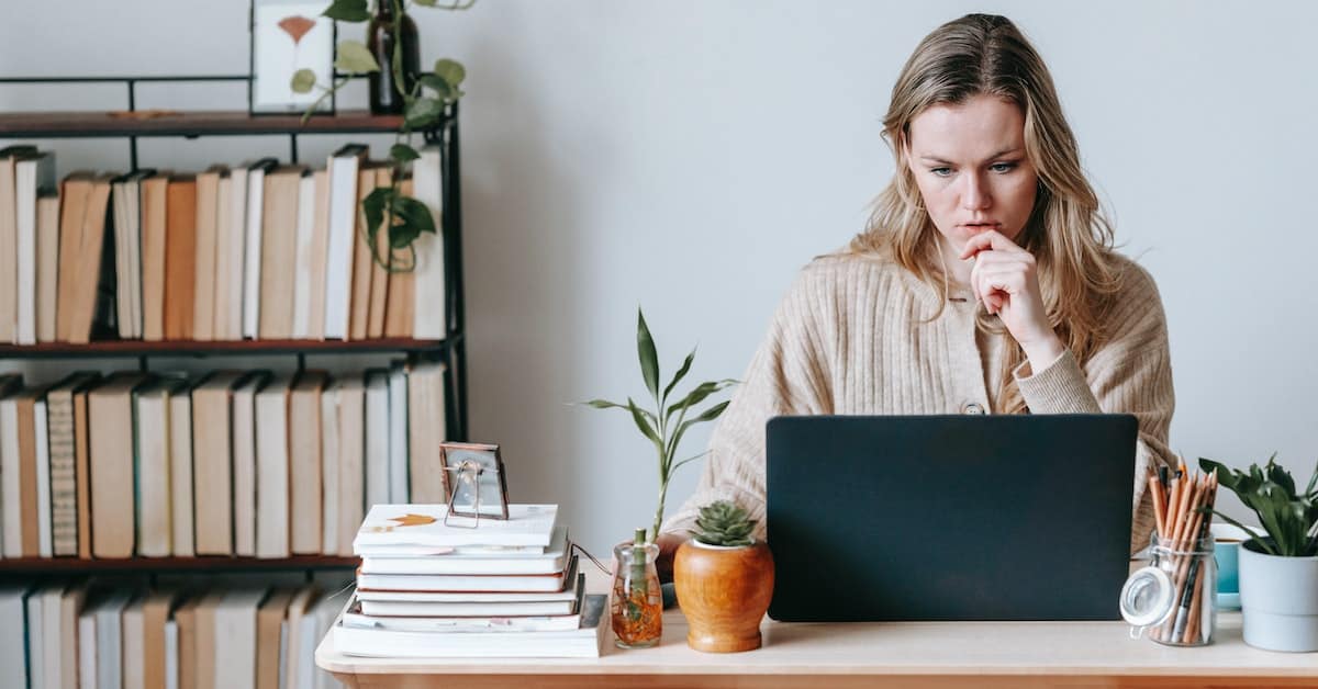 A businesswoman seated at her desk, focused on her laptop.
