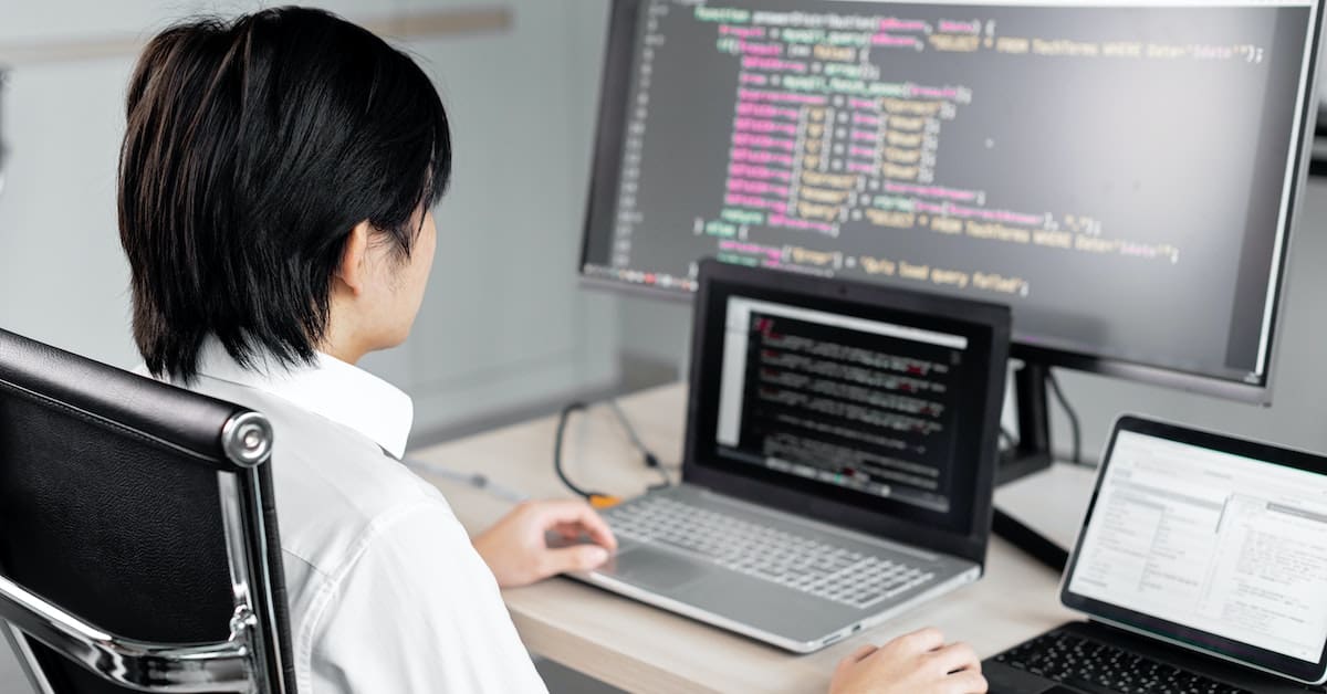A man sits in front of a computer with code on the screen, possibly working with a CSS framework.