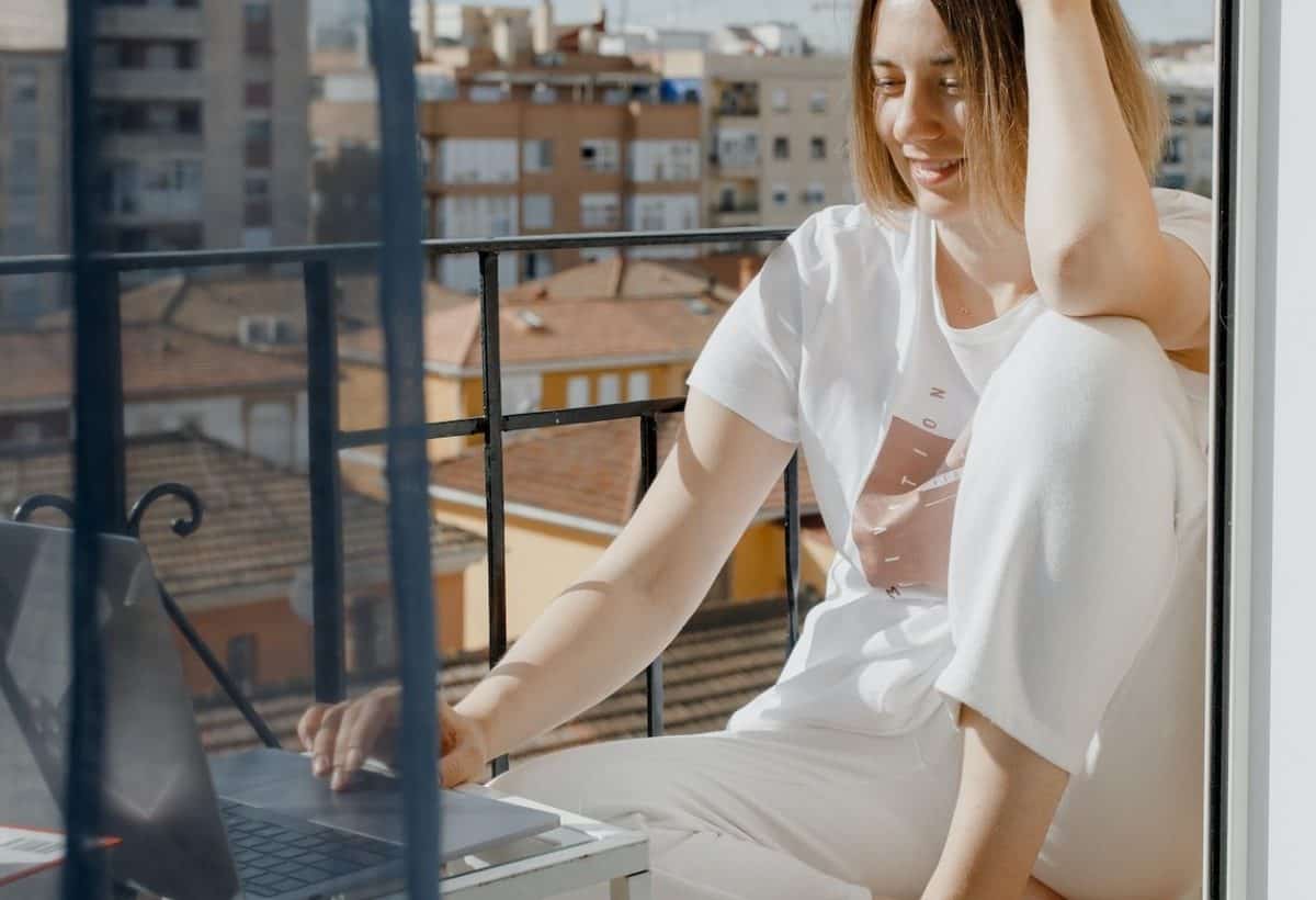 A woman sitting on a balcony with her laptop, working on eCommerce strategies.