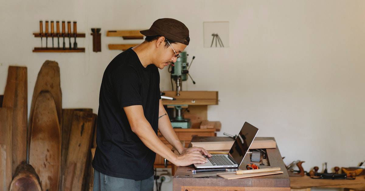 A man working on a laptop in a workshop, utilizing digital tools for his marketing projects.