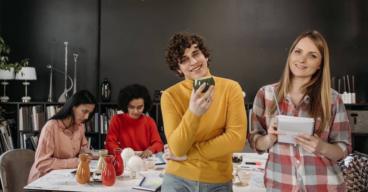 A group of business professionals sitting around a table, distracted by their phones.