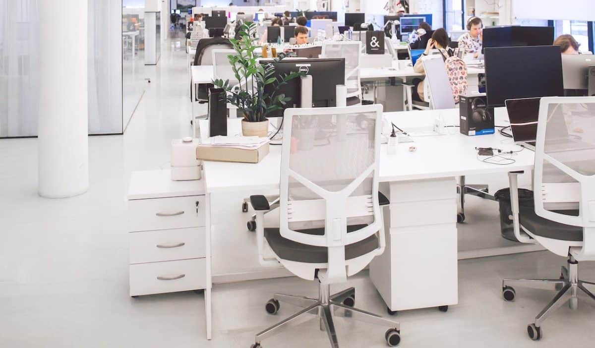 A white office with many people sitting at desks, focused on their e-commerce business.