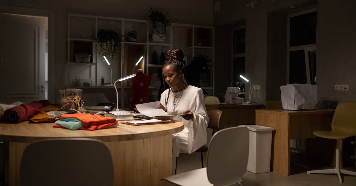 A woman sits at a table with a laptop in front of her, working on her business.