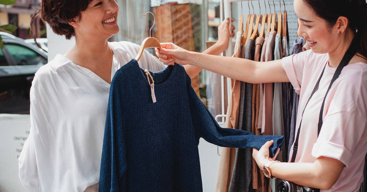 Two women browsing through clothes in a local store.