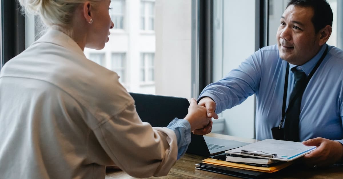 A man shaking hands with a woman in an office setting.