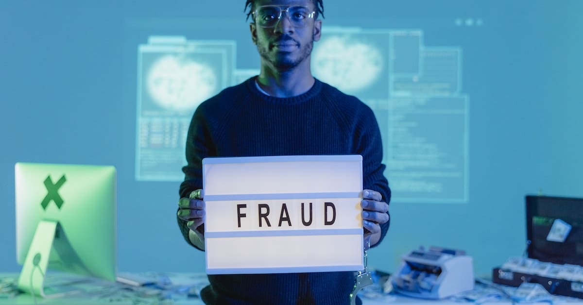 A man at an eCommerce store holding up a sign that says fraud.