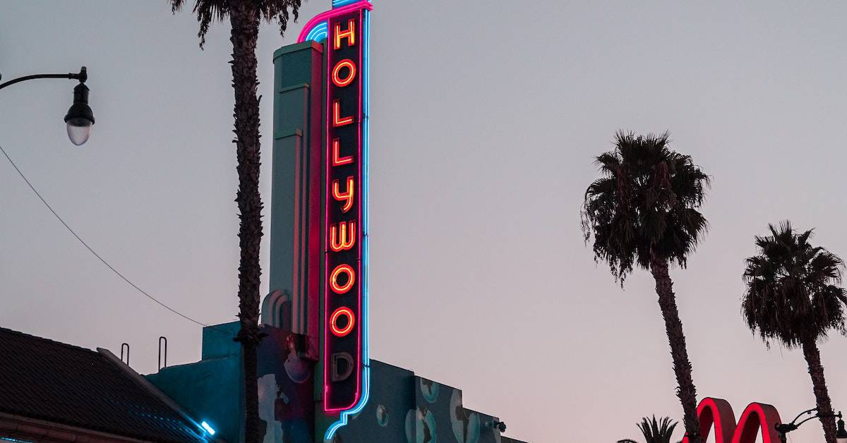 Iconic Hollywood sign at dusk, framed by palm trees in the background.