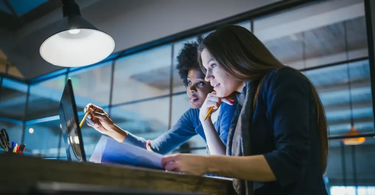 Two women working at a desk in an office, showcasing their versatility and performance.