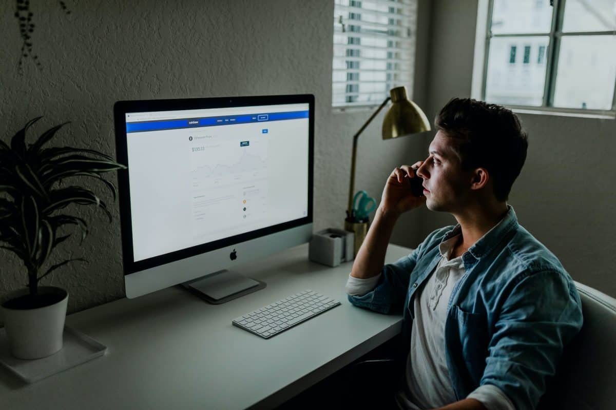 A man sitting in front of a computer looking at Facebook for businesses.