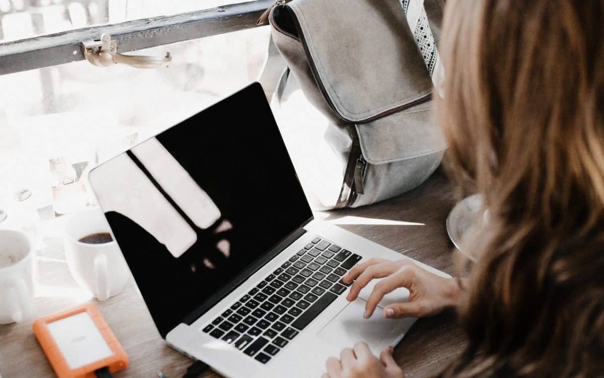A woman using a laptop at a wooden table.