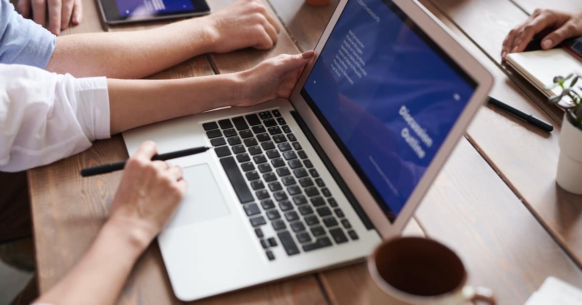 A group of project managers collaborating on a laptop at a table.