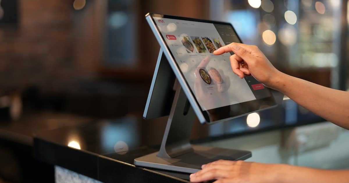 A person in a restaurant is using a tablet to order food, streamlining the process with cafe POS software.