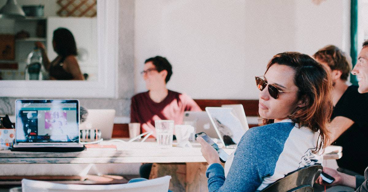 A group of people sitting at a table with laptops trying to get ahead of their competitors.