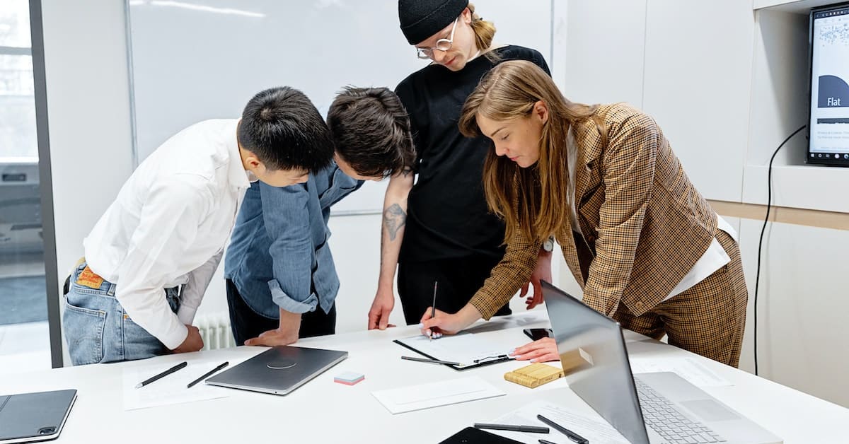 A brand's target audience gathered around a table, looking at a laptop.