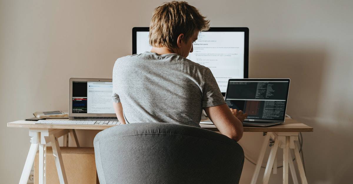 A man sits at a desk with two laptops, showcasing business agility in action.