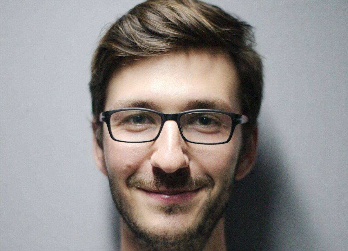 A man in glasses is smiling for the camera at a fintech startup.