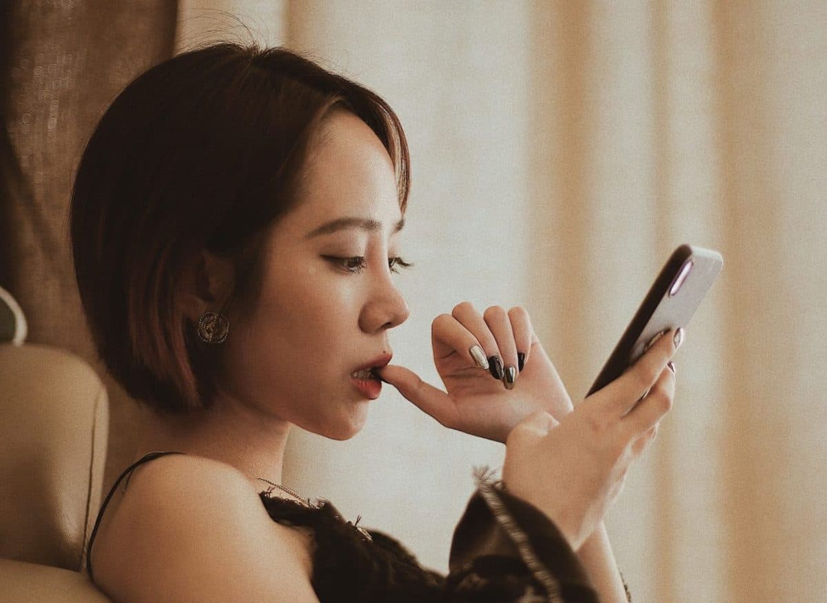 A woman is effectively looking at her phone while sitting in a chair.