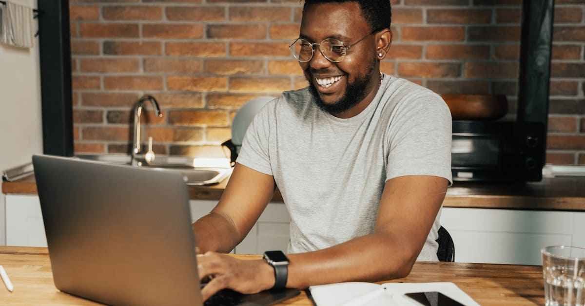 A black man at a table using a laptop for his profitable business.