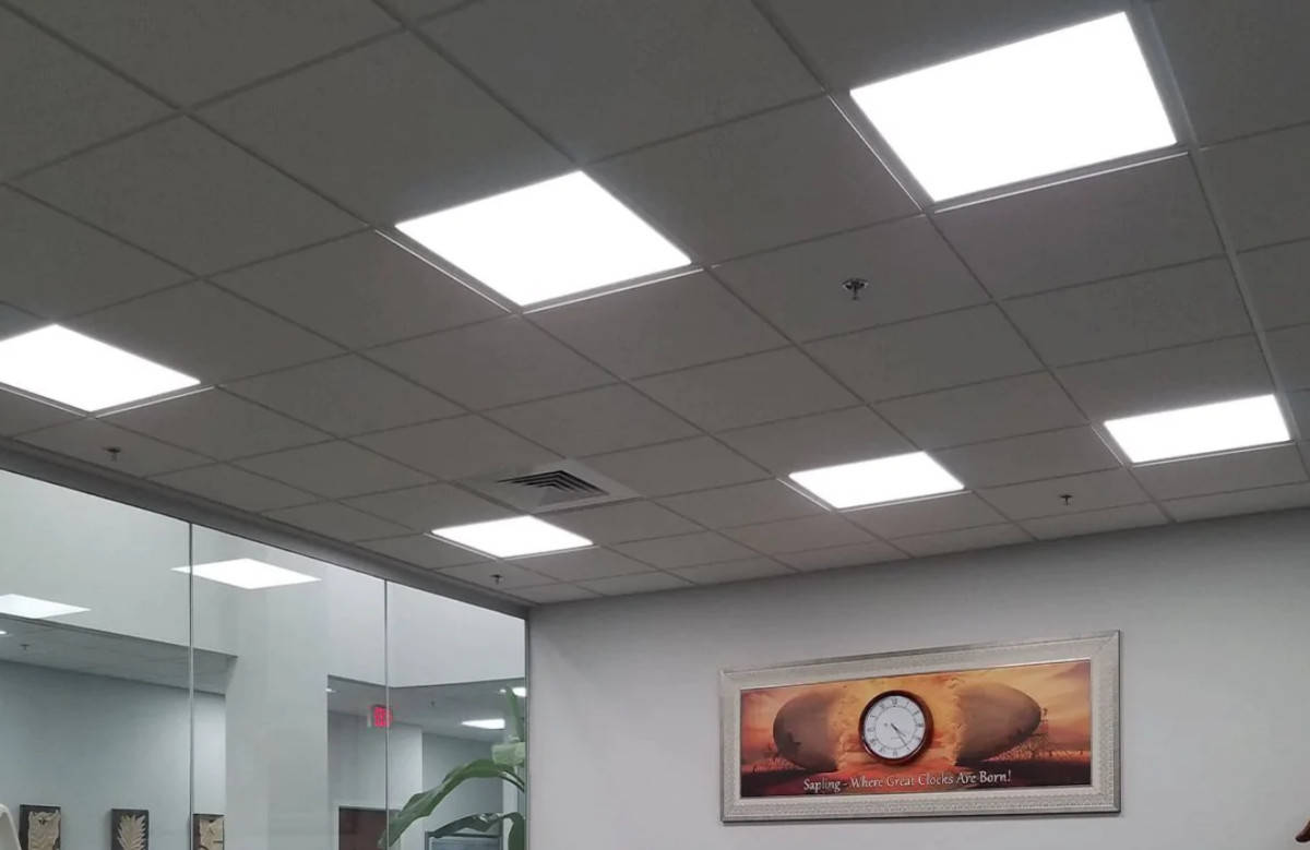 A room with a white ceiling and a clock on the wall, creatively using LED panel lighting for home and office.