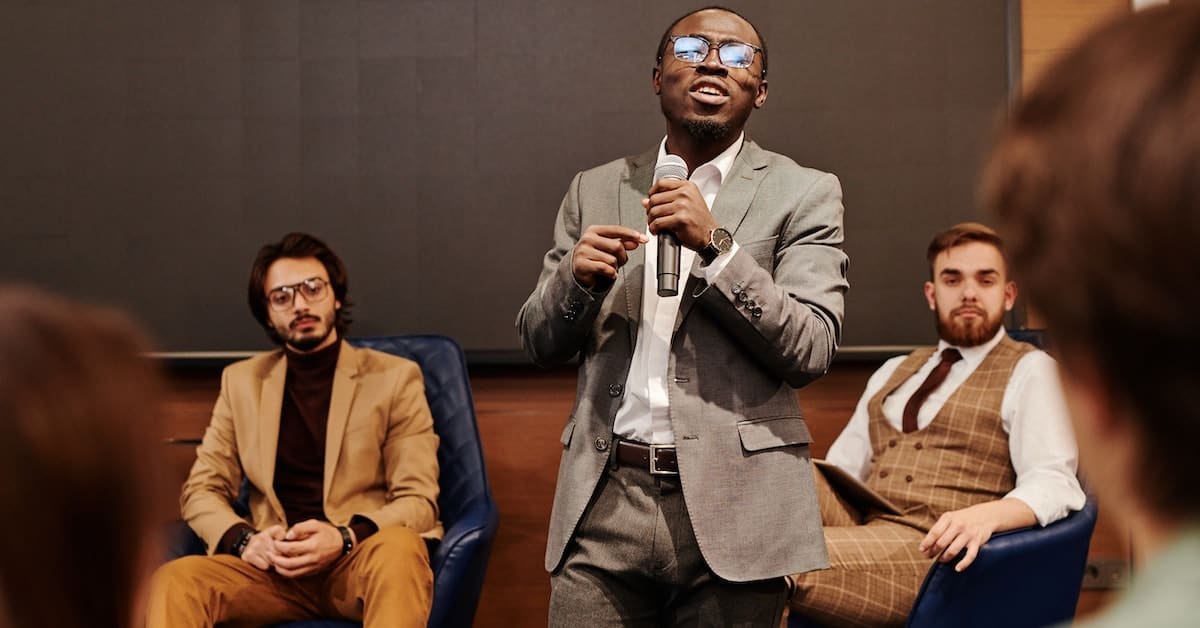 A man in a suit is delivering a presentation on executing the business event of a lifetime.